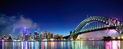 Fireworks at night over the Sydney Harbour with the skyline, Opera House, and bridge in view.